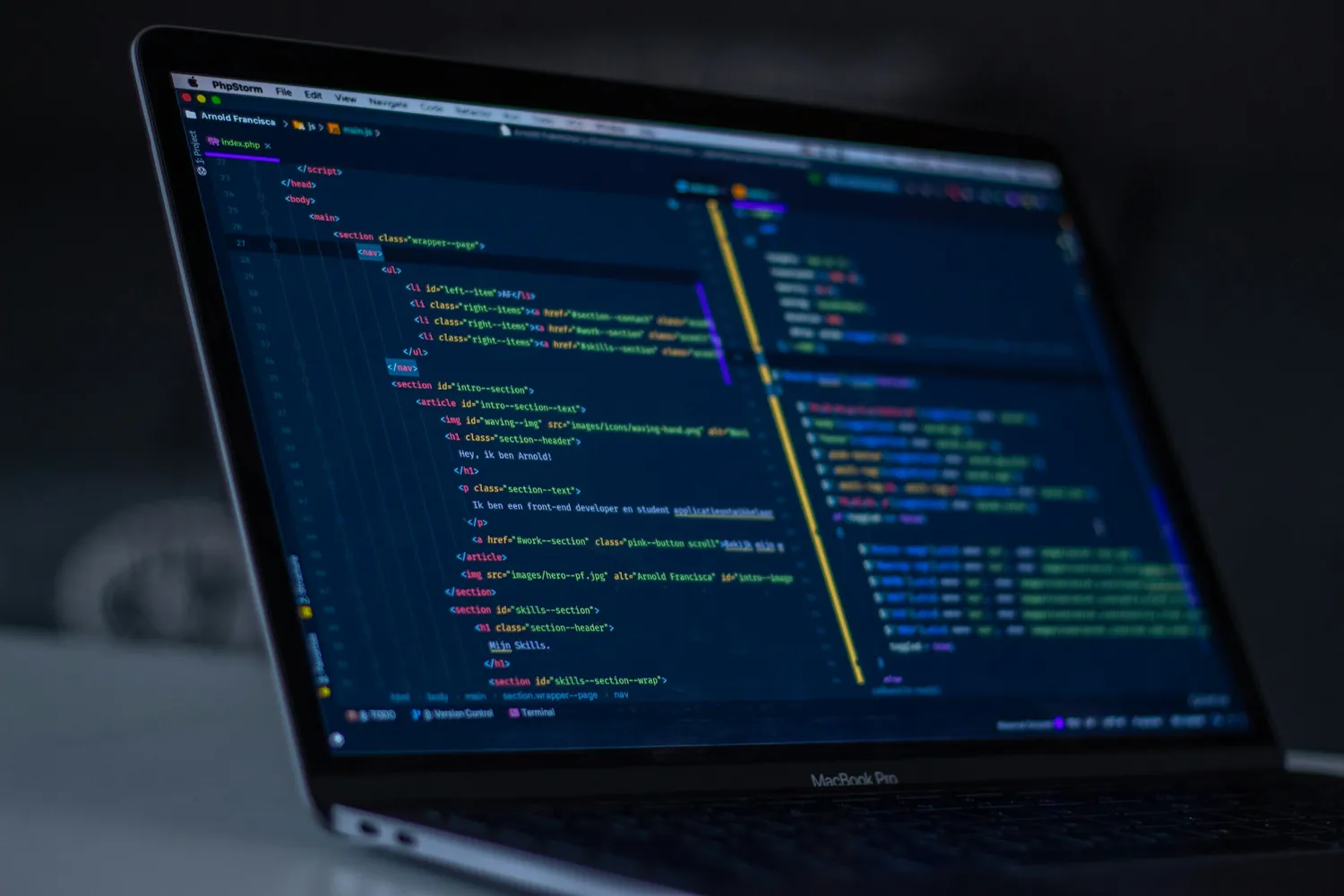 A laptop screen showing HTML and CSS in a code editor, viewed at an angle in a dark room