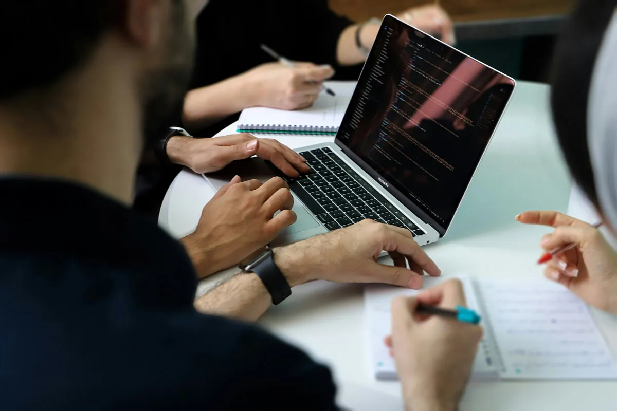 Founders and developers reviewing code on a laptop together while taking notes
