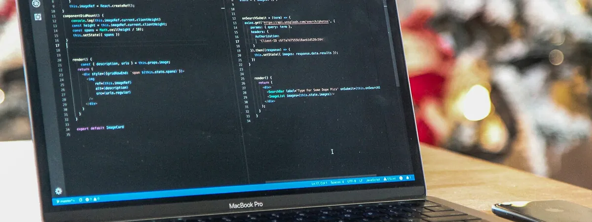 MacBook Pro on a desk showing a code editor with two panes of JavaScript source